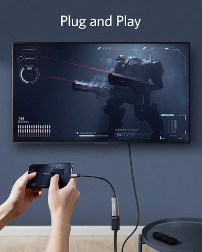 Anker PowerExpand USB-C to DisplayPort adapter connected to a laptop, showing the compact black adapter with cable attached.