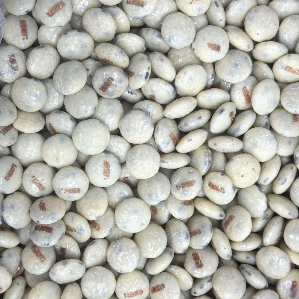 Hershey's Cookies 'N' Creme chocolate drops in a bulk Candy In Bulk bag, showing shiny white and brown candies with textured surface.