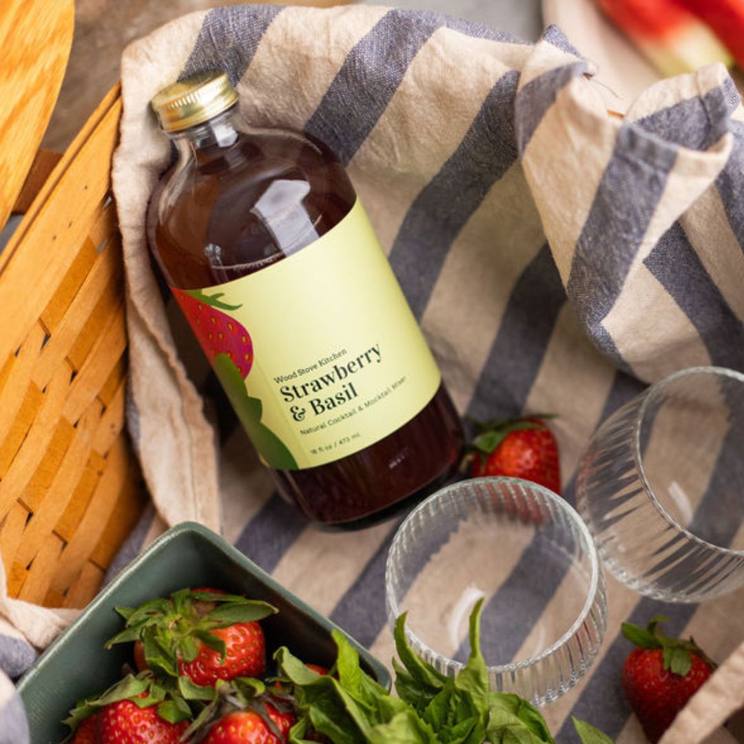 Wood Stove Kitchen strawberry and basil cocktail and mocktail mixer in 16 fl oz bottle, showing fresh strawberries and basil leaves.