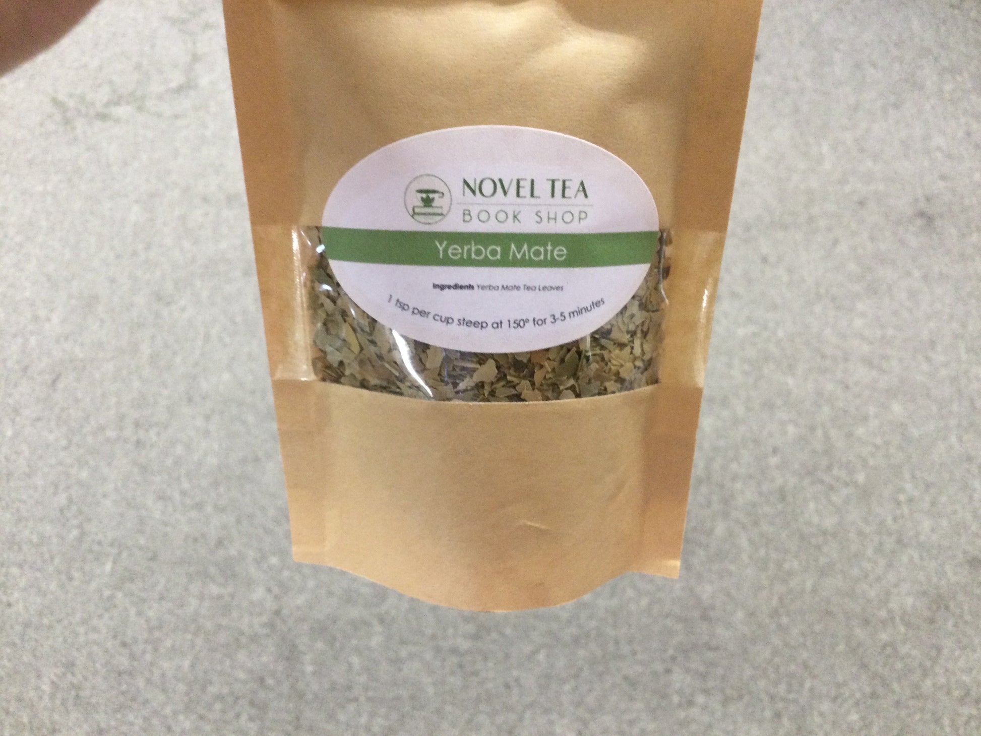 Loose leaf Yerba Mate herbal tea in a jar from Novel Tea Book Shop, showcasing green tea leaves and packaging.