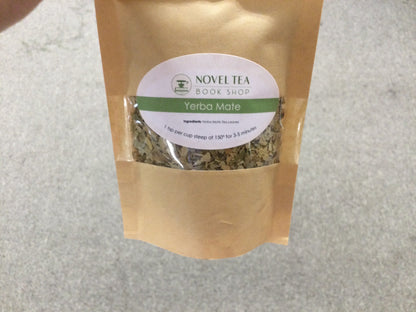 Loose leaf Yerba Mate herbal tea in a jar from Novel Tea Book Shop, showcasing green tea leaves and packaging.