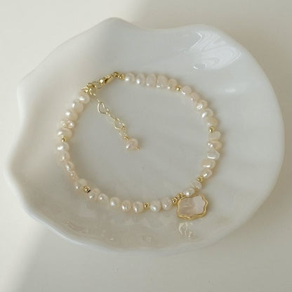 Women's freshwater pearl necklace and bracelet with natural shell accents, delicate jewelry set on a light background