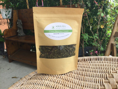 Loose leaf green tea from China in a transparent container, showcasing vibrant green tea leaves for brewing.