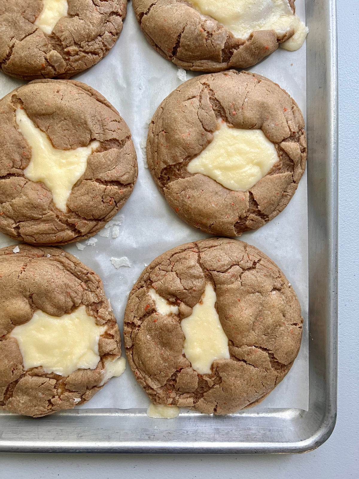 Let's Get Baked Artisan Desserts carrot cake cookies with visible orange carrot flecks and cream cheese frosting on top.
