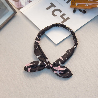 Bunny ears headband with a large bow tie, featuring soft plush ears and a playful design