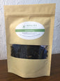 Loose leaf Darjeeling Sungma summer black tea from Novel Tea Book Shop, showcasing dark, aromatic tea leaves in a clear container.