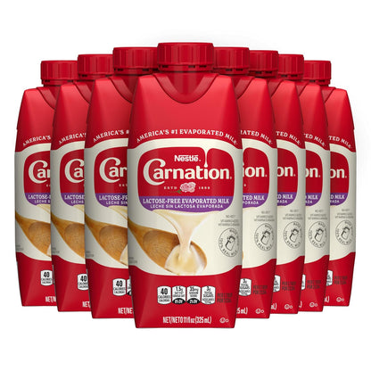 Eight cans of Carnation lactose-free evaporated milk in an 8-pack, showing the product label and packaging.