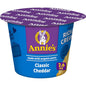 Annie's Homegrown White Cheddar Mac & Cheese microwavable cups, 8-pack, showing creamy cheese sauce and pasta in a cup.