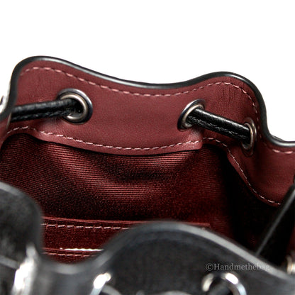 Coach Dempsey Mini black jacquard canvas patch crossbody bucket bag with adjustable strap and signature design.