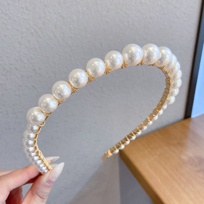 Thin pearl headband with delicate pearls arranged along a slim band