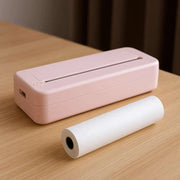 Compact pink portable thermal printer with roll of thermal paper on wooden table