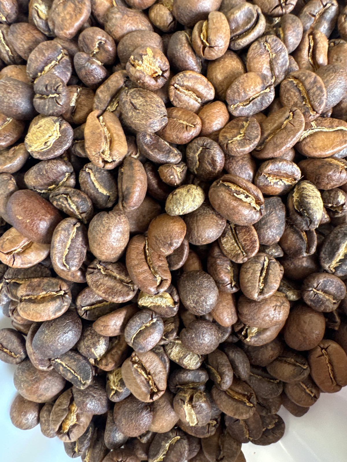 A cup of roasted Morning Crumble Blend coffee from Good Brothers Coffee LLC with coffee beans and a spoon on a rustic wooden surface.