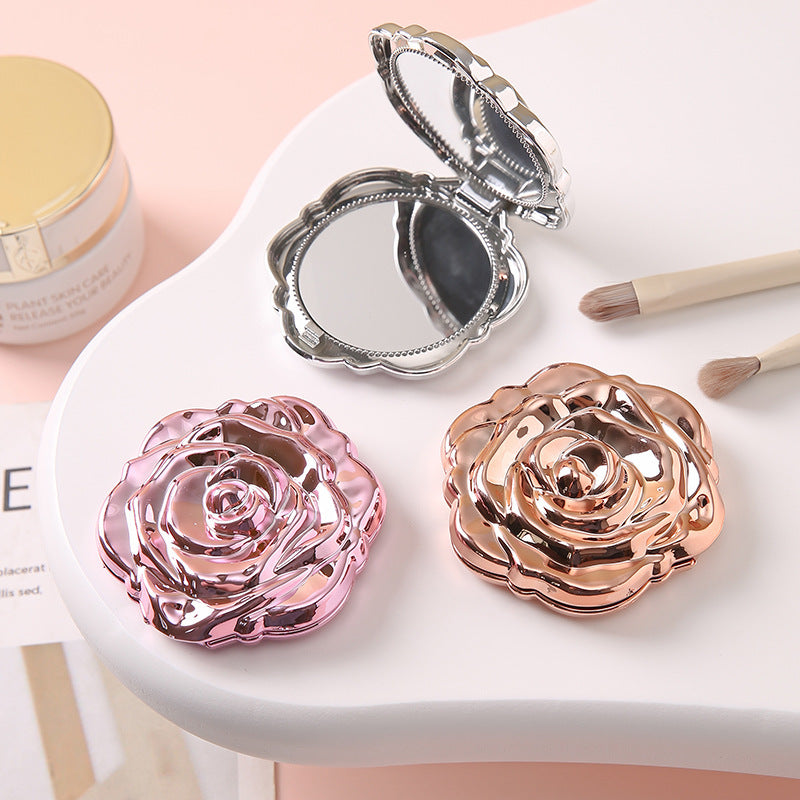 Portable folding mirror with electroplated rose design, shown closed for compact storage