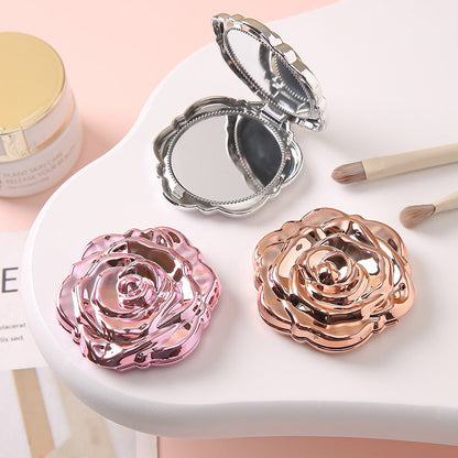 Portable folding mirror with electroplated rose design, shown closed for compact storage