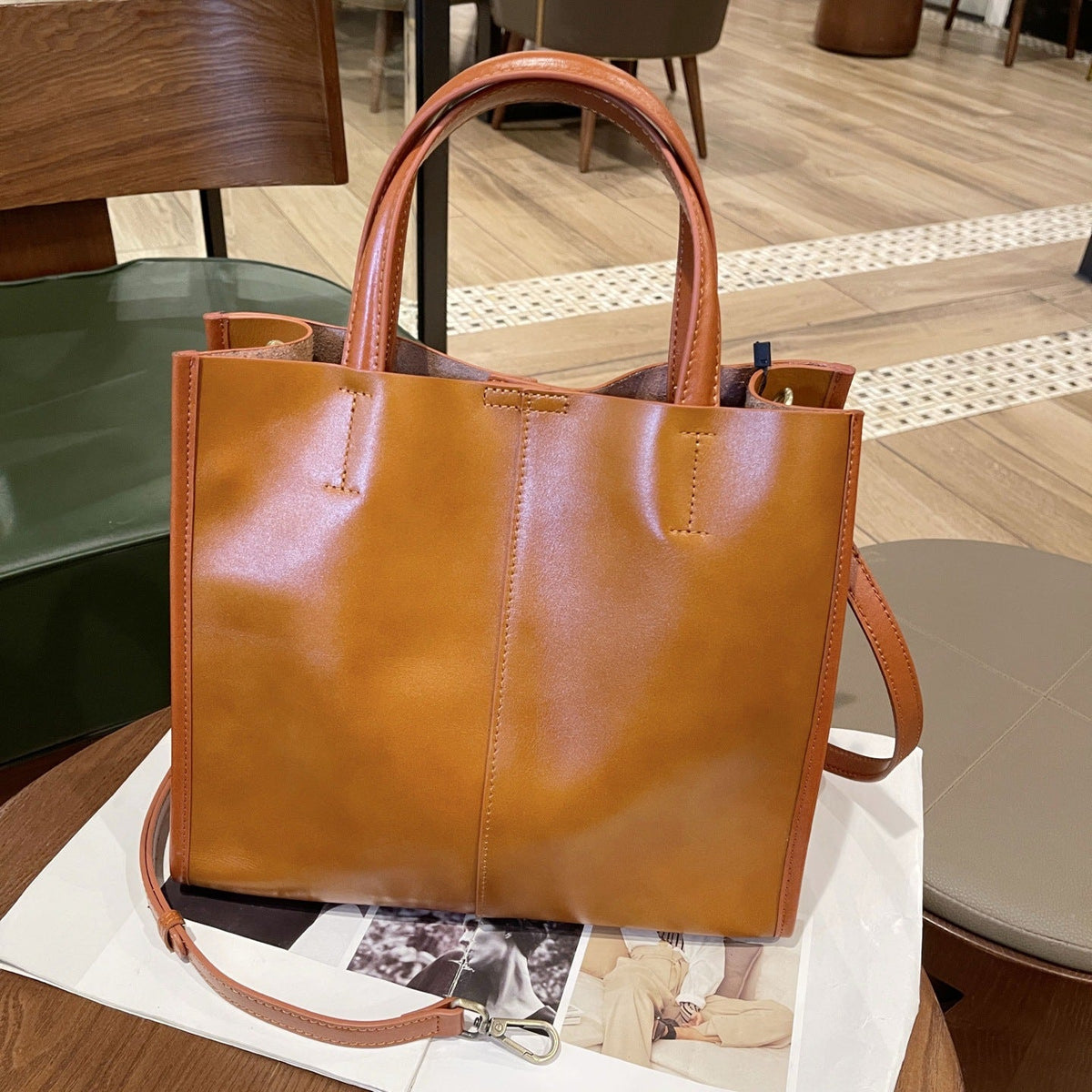 Brown cowhide leather tote bag with single shoulder strap and spacious bucket-style design for women