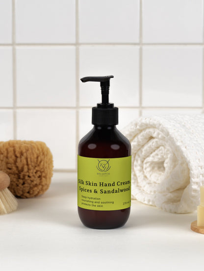 BelleVie Cosmétiques Silk Skin Hand Cream in dark amber pump bottle with lime green label, displayed with bath accessories on white surface.
