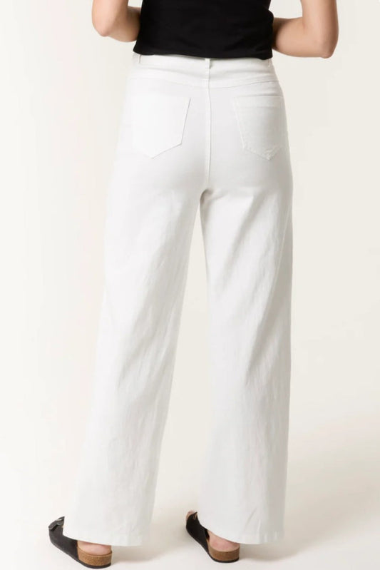 White wide leg trousers from Aftershock London, featuring a relaxed fit and high waist, styled with casual footwear.