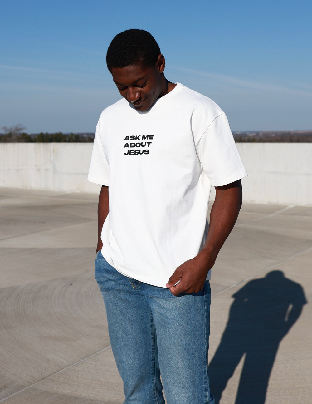 Black heavyweight T-shirt by Elevated Faith featuring bold "Ask Me About Jesus" graphic print on front.