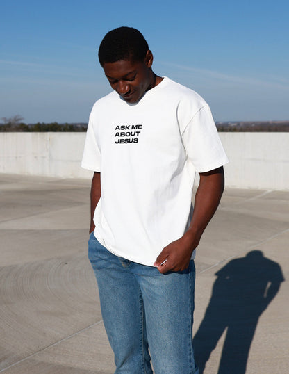 Black heavyweight T-shirt by Elevated Faith featuring bold "Ask Me About Jesus" graphic print on front.