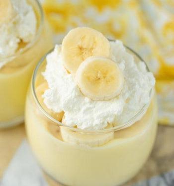 Banana Creme Pudding by AmBari Nutrition served in a bowl with banana slices and whipped cream, showcasing creamy dessert texture.