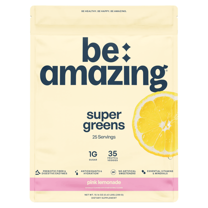 Pink lemonade flavored Be Amazing Super Greens powder in a canister, showcasing vibrant packaging and fresh green ingredients.