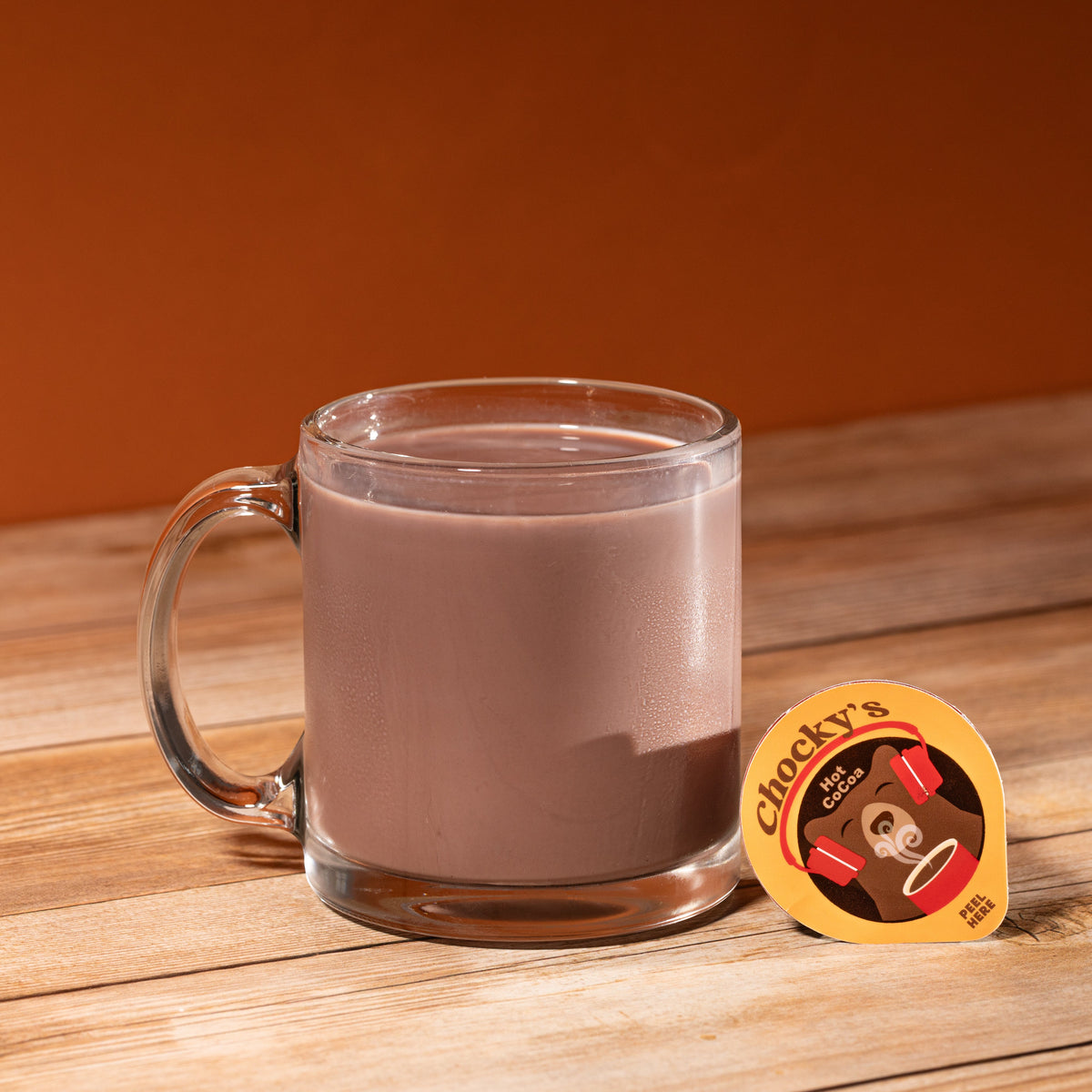 A steaming mug of Chocky's Hot Cocoa from Java House with whipped cream topping, served in a cozy ceramic cup.