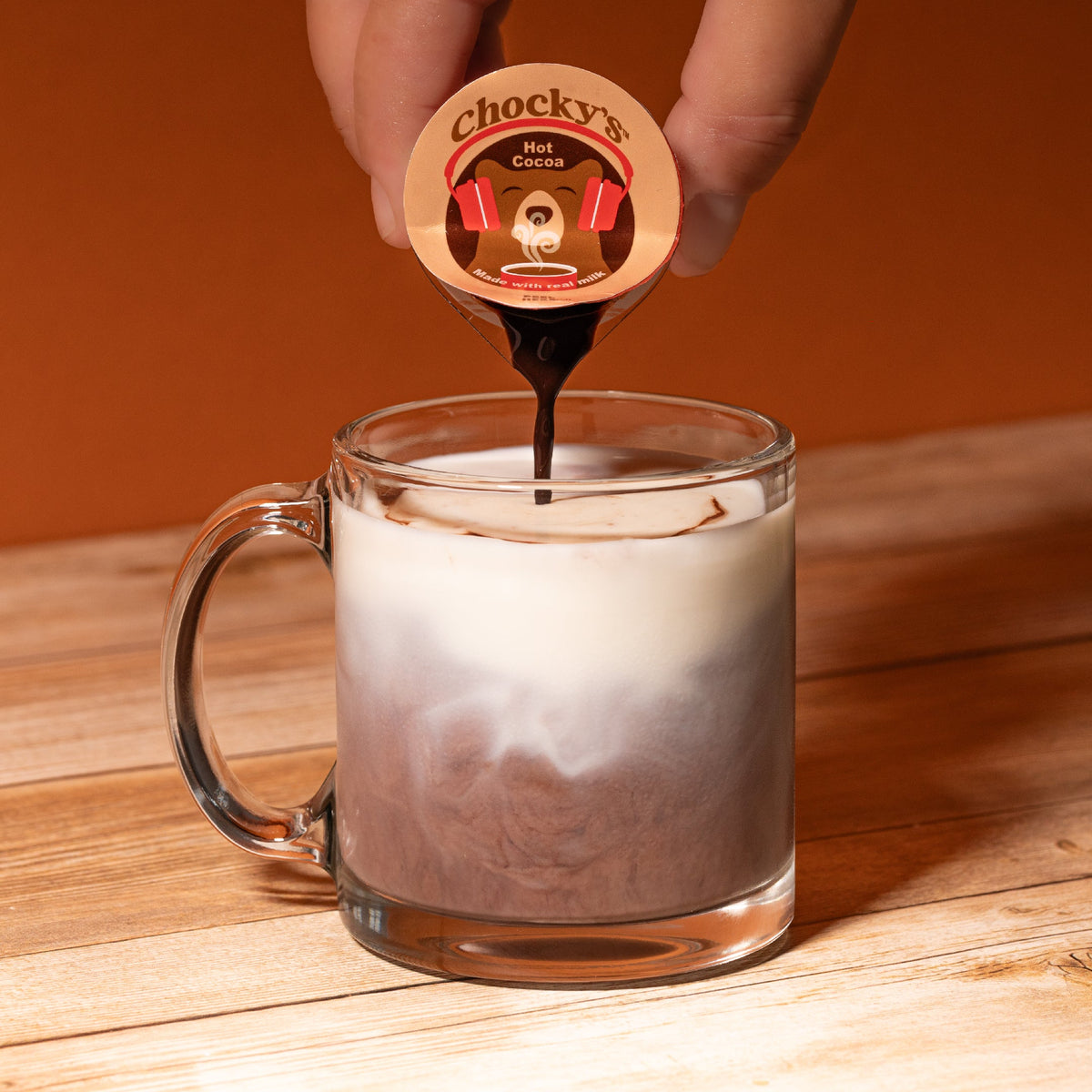 A steaming cup of Chocky's Hot Cocoa by Java House, topped with whipped cream and chocolate shavings, served in a cozy mug.