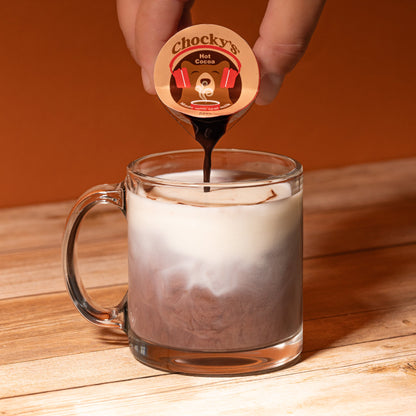 A steaming cup of Chocky's Hot Cocoa by Java House, topped with whipped cream and chocolate shavings, served in a cozy mug.