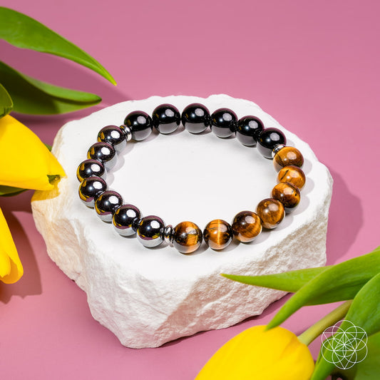 Close-up of The Triple Shield bracelet by Conscious Items, featuring layered silver shields on a black cord.