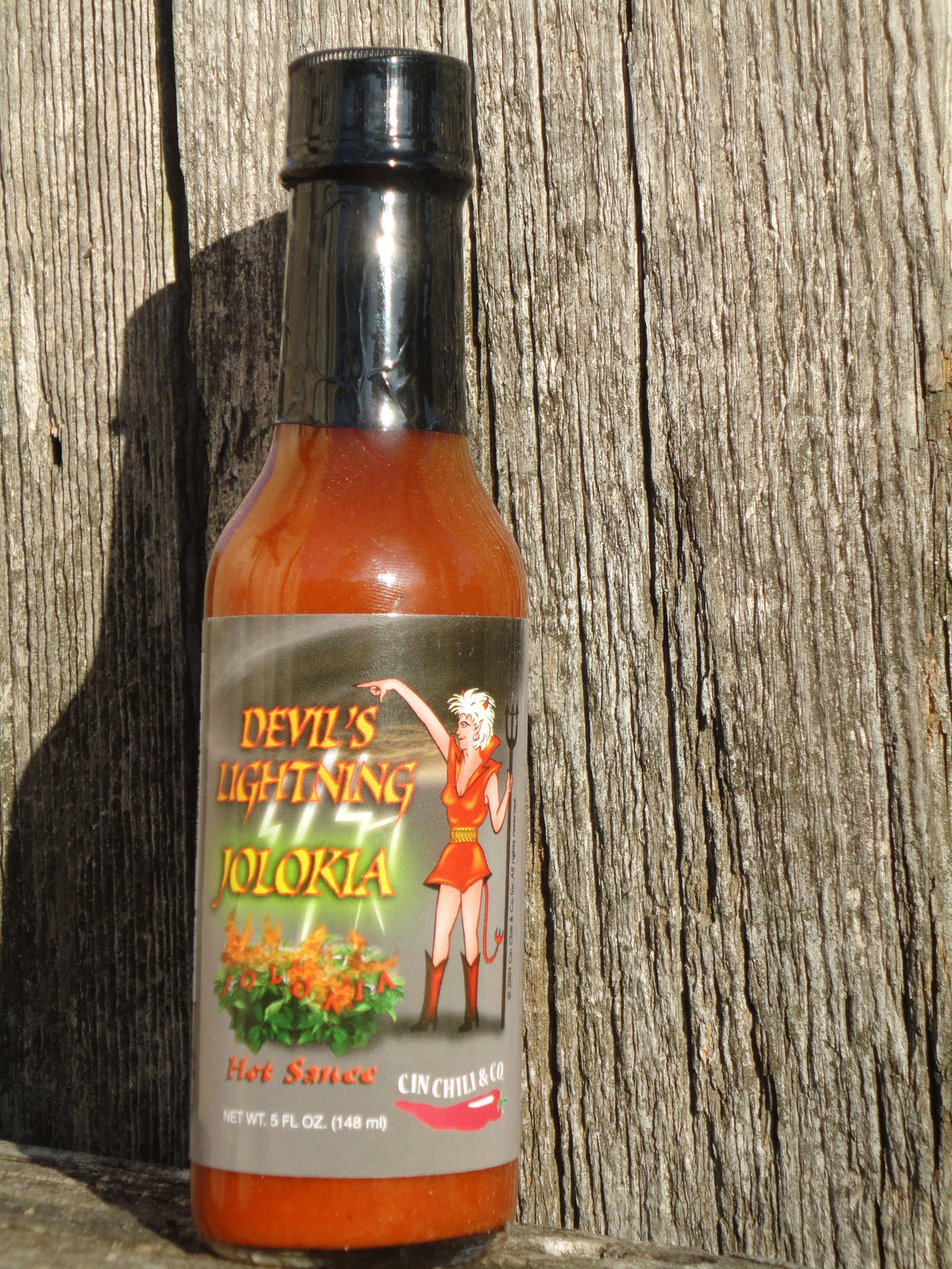 Cinderosa Ranch Devil's Lightning Bhut Jolokia ghost pepper hot sauce bottle on a wooden surface.