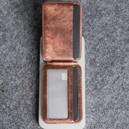 Magnetic cardholder by Robust with brown leather exterior and clear ID window, open to show interior slots for cards on a gray textured background.