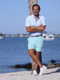 White Water Life Freeport Short Effortless Performance shorts in aqua color, displayed on a dock with a polo shirt.