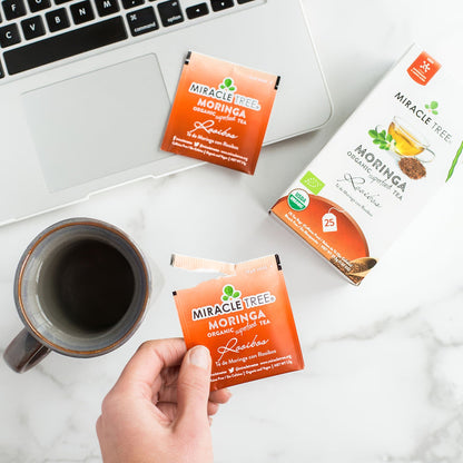 Organic Moringa and Rooibos herbal tea by Miracle Tree, featuring vibrant tea leaves in a clear glass cup.