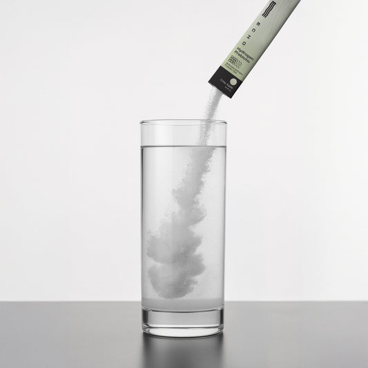 Glass of white hydrogen prebiotic drink mix in a stick pack from Echo Water, showcasing the powder's texture and packaging.