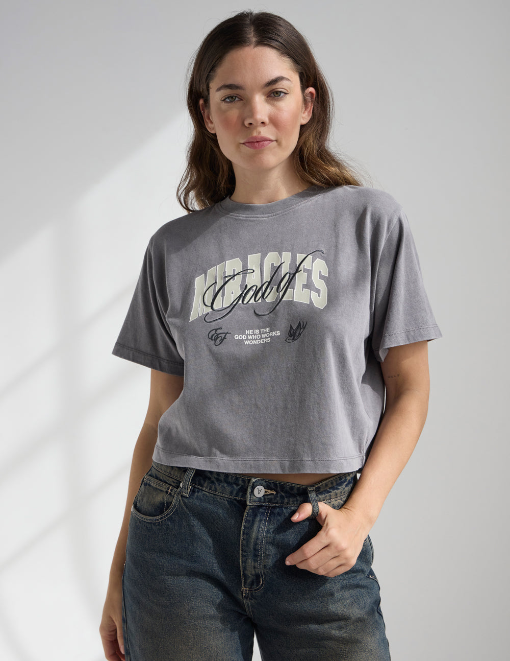 Black cropped women's T-shirt featuring the "God of Miracles" design by Elevated Faith, with a relaxed fit and inspirational message.
