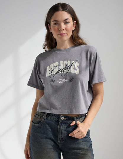 Black cropped women's T-shirt featuring the "God of Miracles" design by Elevated Faith, with a relaxed fit and inspirational message.