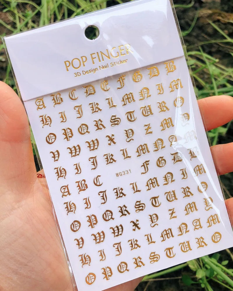 Black Old English font nail art stickers showing gothic alphabet letter transfers on a clear sheet for decorative nail designs.