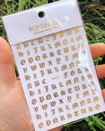 Black Old English font nail art stickers showing gothic alphabet letter transfers on a clear sheet for decorative nail designs.