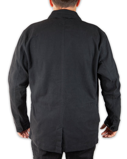 Black Heston Chore Coat by Off The Grid Surplus, featuring durable fabric and classic workwear style, shown on a hanger.