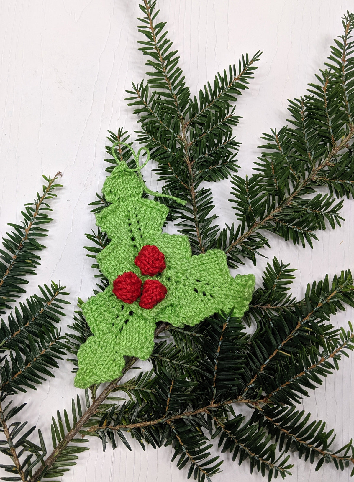Knit Holly Ornament pattern by Darn Good Yarn featuring a festive green and red holiday Christmas decoration for knitting projects.