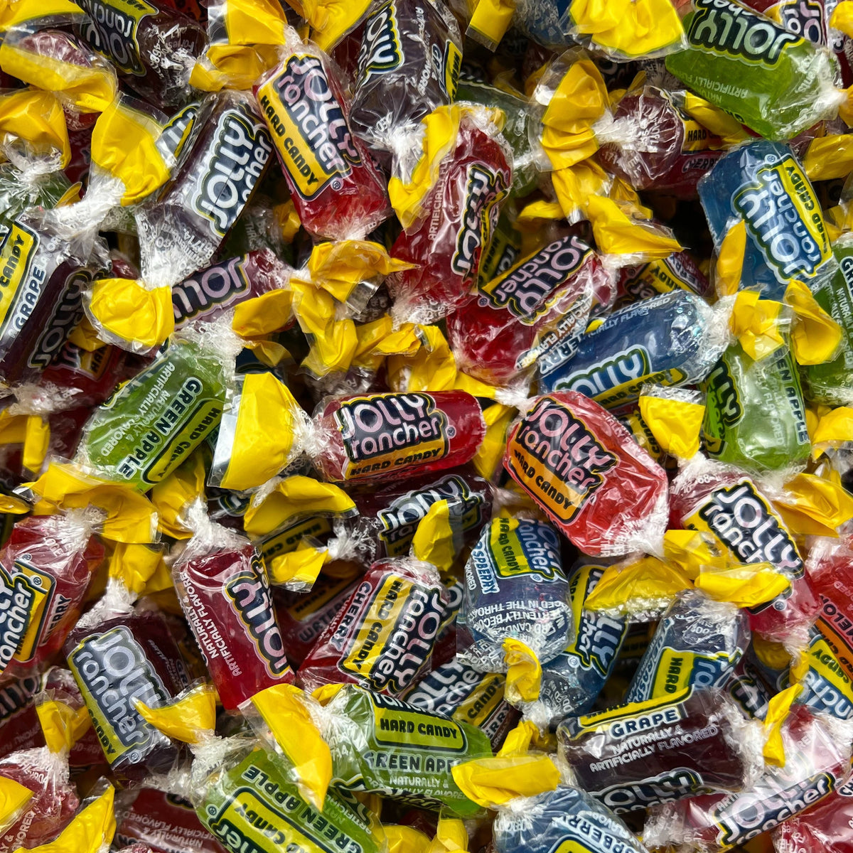 Assorted Jolly Rancher hard candies in a bulk Candy In Bulk bag, featuring colorful fruit-flavored candies in various shapes.