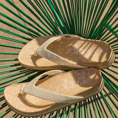 Fleks West Beach Flip Flop in oatmeal color, showing the casual slip-on design and textured sole on a sandy beach setting.