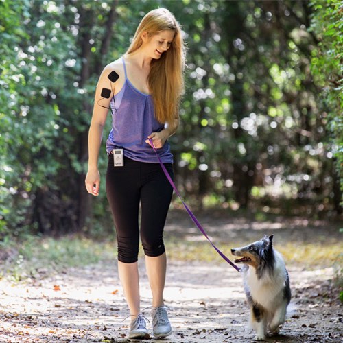 iReliev TENS Unit for pain relief and muscle recovery, shown in use on a person's shoulder in a lifestyle setting.