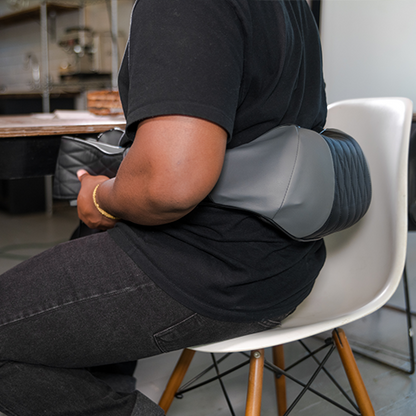 iReliev Shiatsu neck and back massager used on a person's shoulders in a home setting, showing massage nodes and adjustable straps.