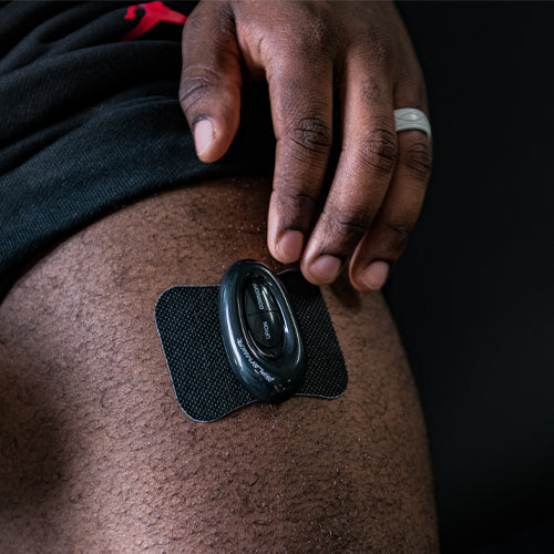 iReliev WiTENS Mini Wireless TENS Unit used for pain relief, shown in a lifestyle setting with user applying the device on their arm.
