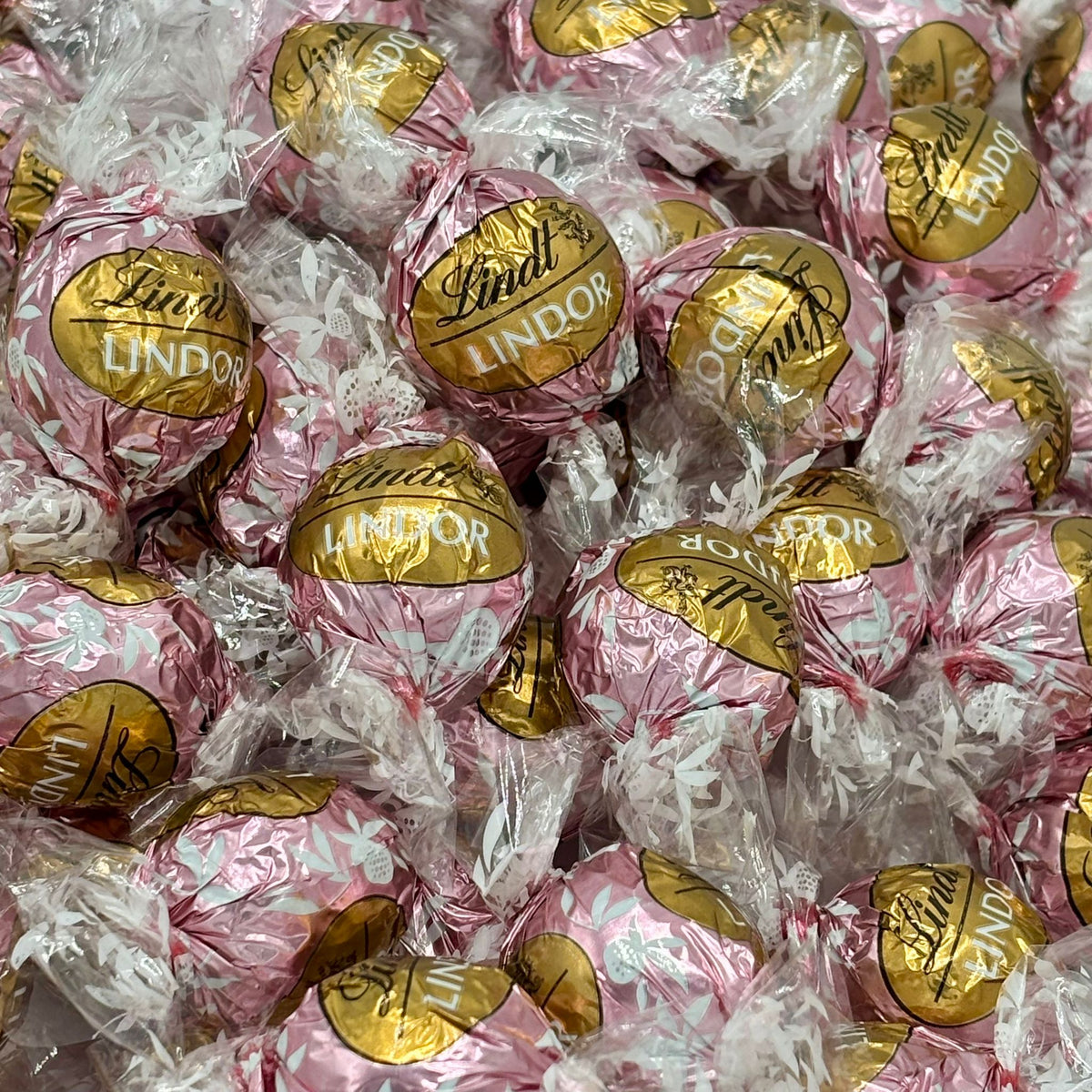 Lindt LINDOR Neapolitan white chocolate truffles in a bulk value bag, showcasing smooth, creamy chocolate with pink, white, and brown layers.