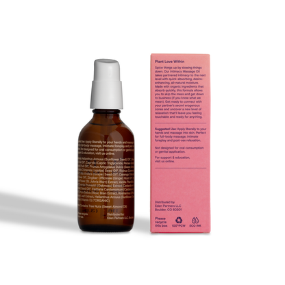 Foria massage oil with organic botanicals shown in a clear glass bottle, with botanical ingredients visible in the background.