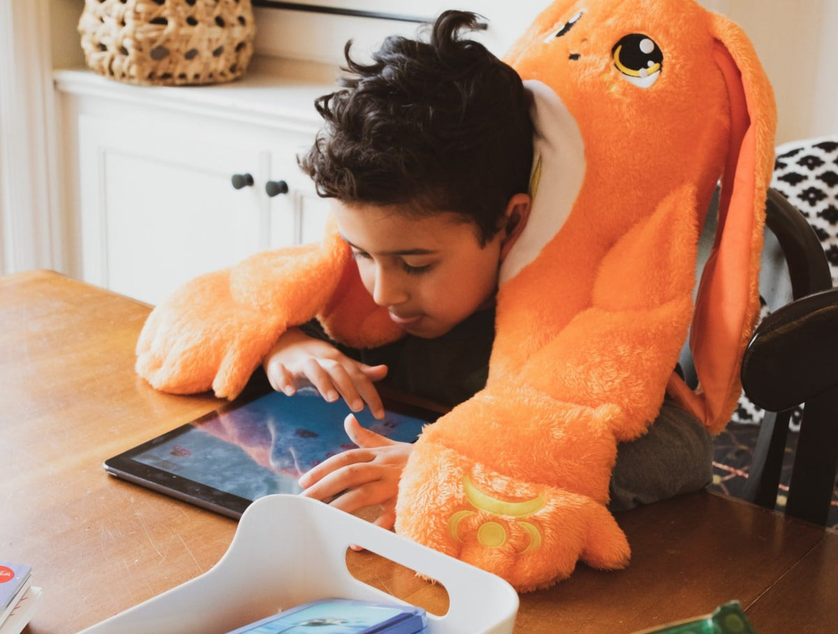 Orange Nova 5lb Hugger Plush from Moon Pals, showcasing a soft, cuddly stuffed animal in a cozy lifestyle setting.
