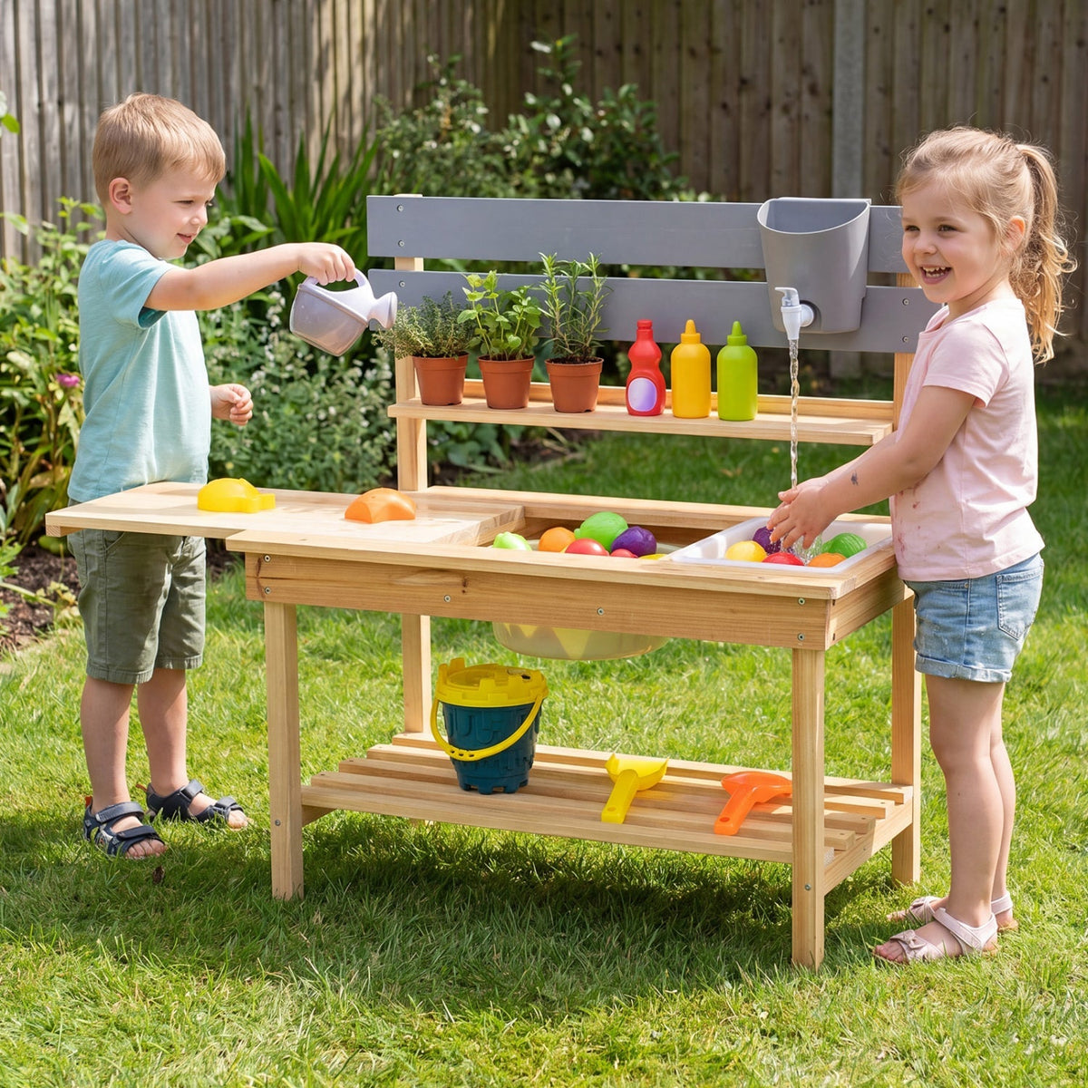 Outdoor kids mud kitchen play set with extended tabletop and water tank, featuring colorful utensils and natural outdoor environment.