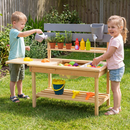 Outdoor kids mud kitchen play set with extended tabletop and water tank, featuring colorful utensils and natural outdoor environment.
